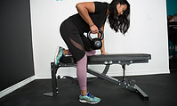 Woman performing a dumbell row on a weight bench