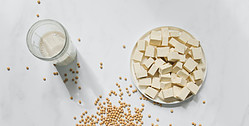 Good source of vitamin B12 - glass of soya milk, bowl of tofu and dried soy beans
